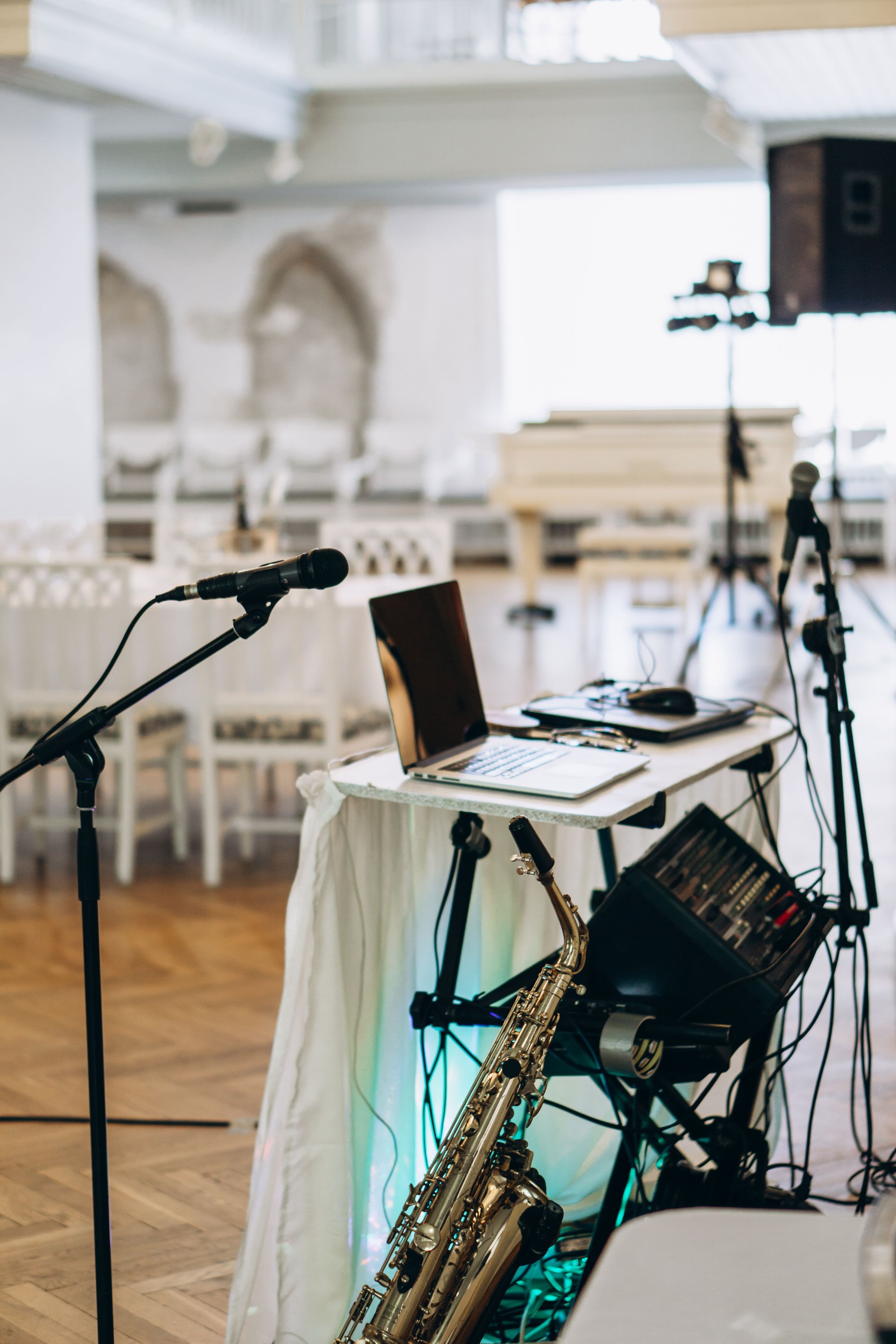 Elegant music setup with laptop, saxophone, and microphones prepared for a live performance in a sophisticated event venue wedding DJ musician